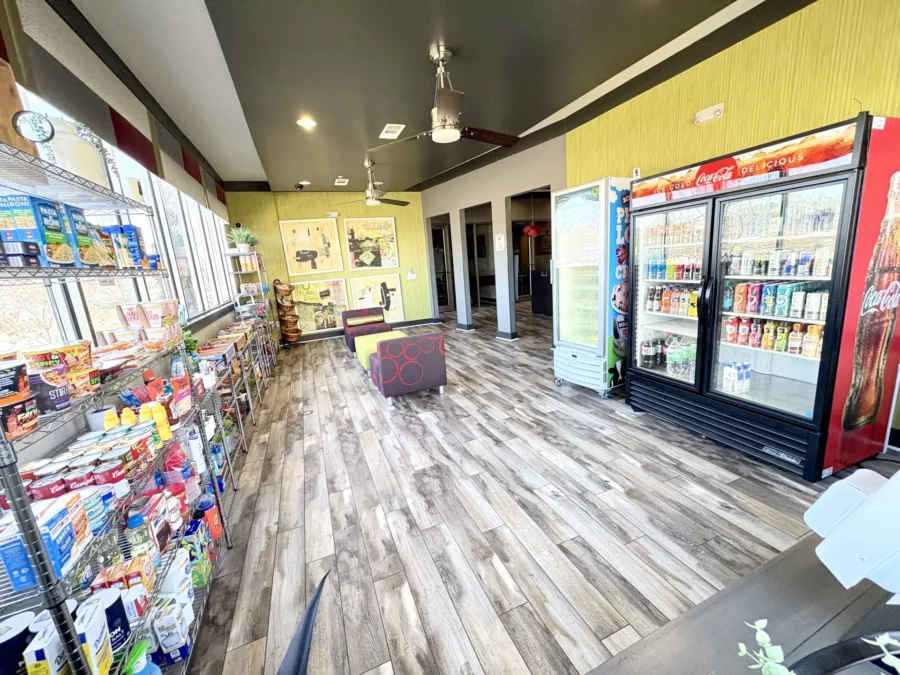 Community store with grocery essentials, beverage cooler, and ice cream freezer.