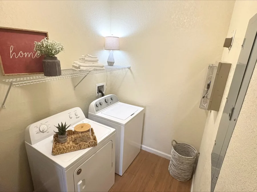 apartment utility room with full sized washer and dryer and a wire shelf